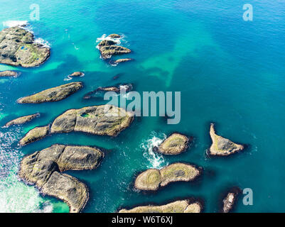 Vivid emerald-green water at Ballintoy harbour along the Causeway Coast in County Antrim. Rugged coastal landscape of Northern Ireland. Stock Photo