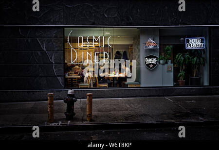 New York City, USA, May 2019, women having dinner in Cosmic Diner in Hell's Kitchen view from the street at nighttime Stock Photo