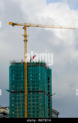 High-rise building, crane, blue sky, white clouds. Construction of buildings with construction cranes. Condominium Construction Stock Photo