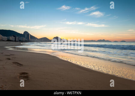 Early morning Copacabana beach in Rio de Janeiro with the Sugarloaf mountain in the background just before sunrise with deep orange and blue colours Stock Photo