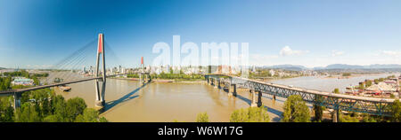 Aerial panoramic view of Pattullo Bridge and Skytrain Bridge over the Fraser River. Taken in Surrey, Greater Vancouver, British Columbia, Canada. Stock Photo