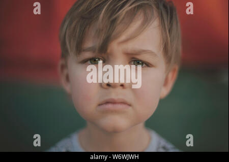 A child with green hazel eyes looks into the camera with a serious expression Stock Photo