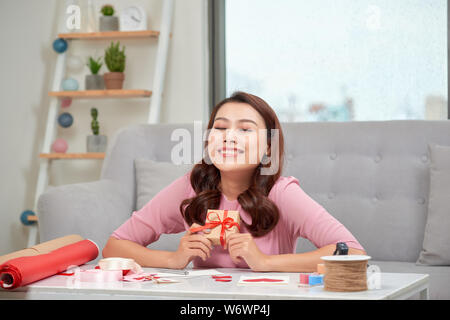 Happy young woman pressing gift box to her chest Stock Photo