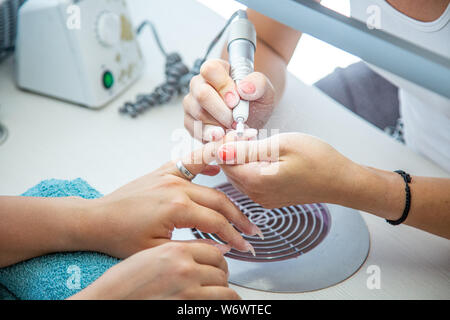 Close up of Beautician Hands with Electric Nail Drill in Beauty Manicure Salon Stock Photo