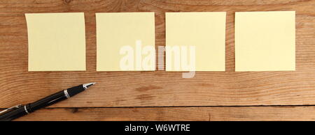 four yellow notes on a wooden table Stock Photo