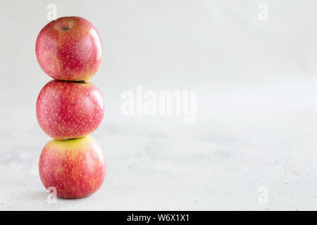Stack of three apples on light gray background with copy space Stock Photo
