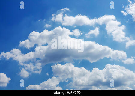 Fluffy white clouds float across the blue summer sky Stock Photo