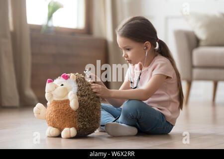 Little girl play doctor and treats hedgehog stuffed toy Stock Photo