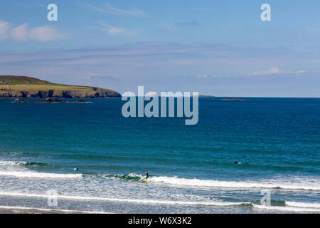 Surfers in Whitesands Bay with South Bishop lighthouse and Ramsay Island beyond, Pembrokeshire Coast National Park, Wales, UK
