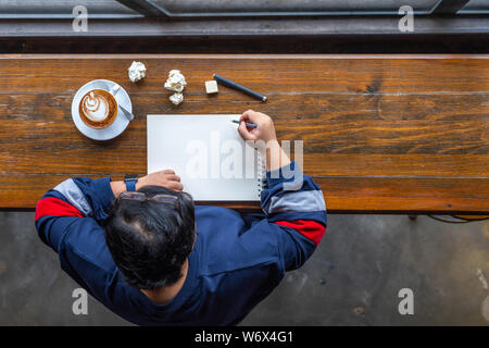 Top view of Asian freelancer drawing on sketchbook at coffeeshop Stock Photo