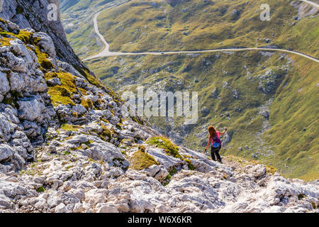 Woman tourist descending from Mangart (or Mangrt) peak towards Mangart saddle (Mangartsko sedlo) via the Italian route - late afternoon with warm sunl Stock Photo