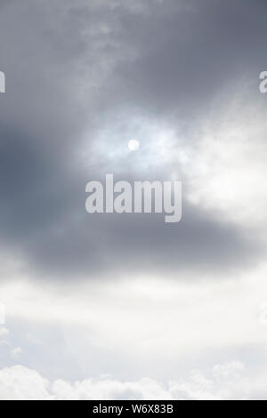 Sun behind grey clouds on a hazy day Stock Photo