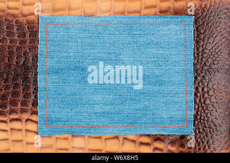 Blank jeans frame. Denim patch with orange thread seam on brown skin. With space for design, text place. Stock Photo