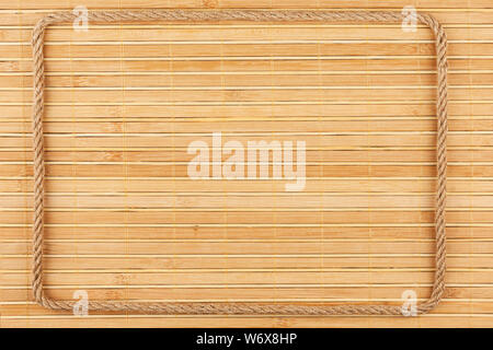 Frame of rope, lies on a background of a bamboo mat, with place for your text. Top view Stock Photo