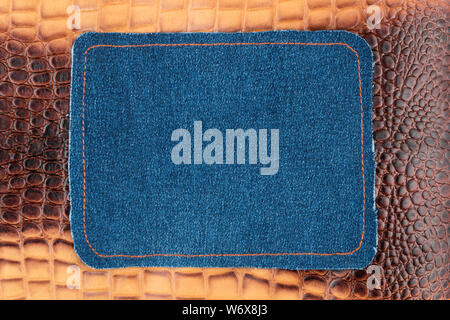 Blank jeans frame. Denim patch with orange thread seam on brown skin. With space for design, text place. Stock Photo