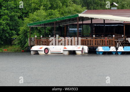 Close view of a artificial lake with shelter and boats on a rainy day in rila park near town Dupnitsa, Bulgaria Stock Photo