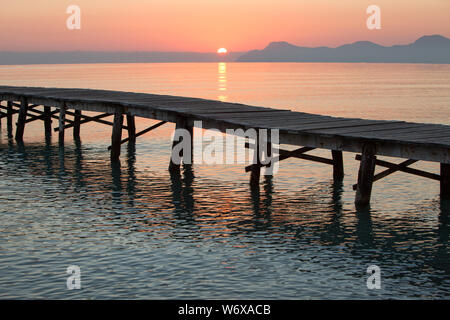 Sunrise at the long wooden jetty of Playa de Muro in the bay of Alcudia, Europe, Spain, Mallorca, north, sun is kissing the sea Stock Photo
