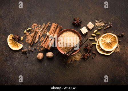 Winter Spices and Brown Sugar on dark rustic background, top view, copy space. Mulled wine or Christmas seasonal baking ingredients - aroma spices. Stock Photo