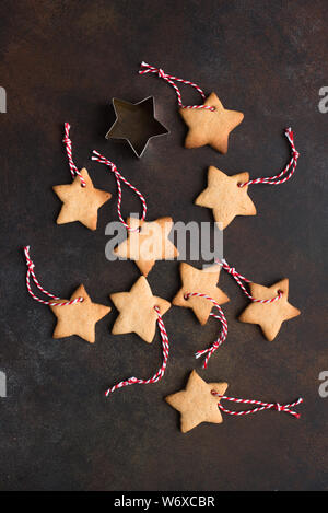 Christmas Background - Christmas star shaped gingerbread cookies with red ropes and golden balls for Christmas tree decoration on rustic background, t Stock Photo