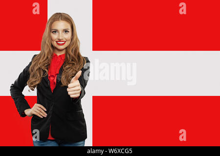 Travel and learn danish language concept. Smiling woman student showing thumb up against the Denmark flag background Stock Photo