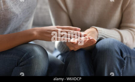 Close up image adult daughter touches hands of aged mother