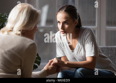Daughter holding hands aged mother having heart-to-heart talk Stock Photo