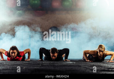 Team of sportive people doing pushups in crossfit gym Stock Photo