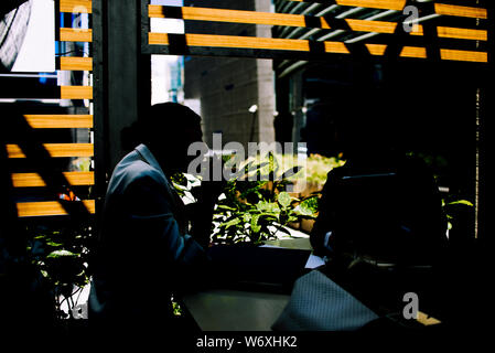Male and female business partners sitting in cafe and discussing contract while using digital tablet Stock Photo