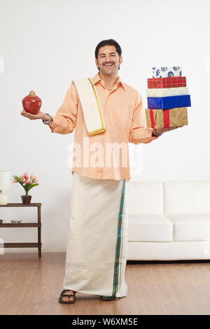 South Indian man holding gift boxes with piggy bank Stock Photo