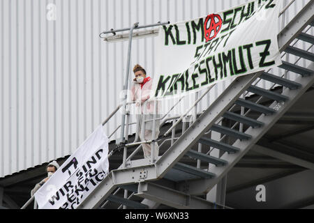 Mannheim, Germany. 03rd Aug, 2019. Activists stand on the stairs at the occupied coal conveyor belt, where large banners hang. Activists from the Ende Gelande organisation have occupied the coal conveyor belt on the large coal power plant in Mannheim. They also block the main entrance of the plant, calling for an end to the use of coal in energy production and the use of renewable energy sources. Credit: Michael Debets/Pacific Press/Alamy Live News Stock Photo