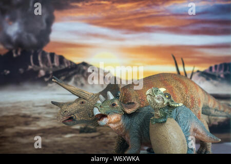 Family of triceratops with jurassic land into background. Mother and sons with love. Stock Photo
