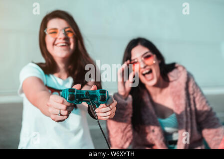 Two female young friends playing video games with controller Stock Photo