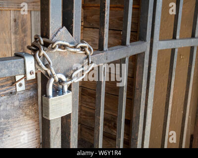 Silver lock and thick chain barring entrance to wooden door Stock Photo