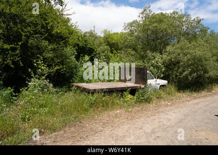 Rusty flatbed truck broken down and hitting on side of dirt road Stock Photo