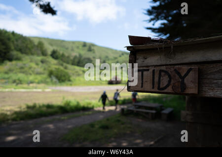 Sign labeled tidy sitting on wooden home on a farm with people walking in background Stock Photo