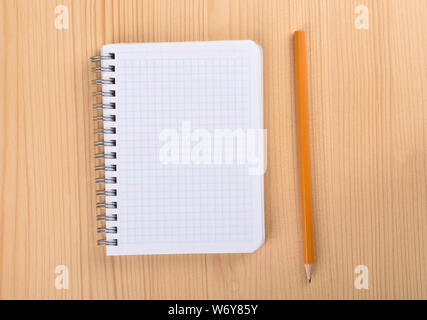 Close up notepad. Squared paper notebook on wooden table top view. Pencil near the notebook. Stock Photo