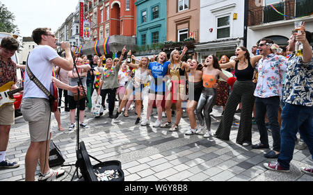 Brighton UK 3rd August 2019 - A singalong in New Road after the annual Brighton and Hove Pride parade starting from the seafront before heading through the city and on to Preston Park where Kylie Minogue is due to perform in the evening . Hundreds of thousands of visitors are expected to take part in this years event over the weekend . Credit : Simon Dack / Alamy Live News Stock Photo