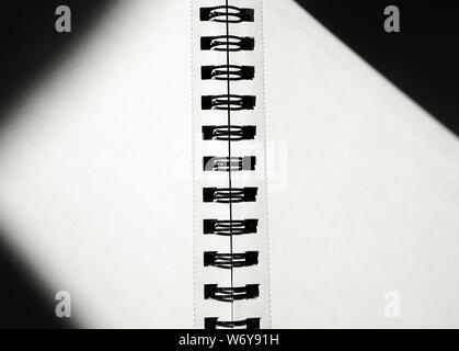 Open notebook on spring in the center with black blurry shadow in edges.  Textured paper shadow concept copy space. Shade from sunlight by the window. Stock Photo