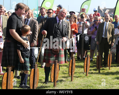 The Prince of Wales, known as the Duke of Rothesay while in Scotland, (front right) watches strongman Luke Stoltman as he lifts heavy stones onto barrels at the Mey Highland & Cultural Games at the John O'Groats Showground in Caithness. Stock Photo