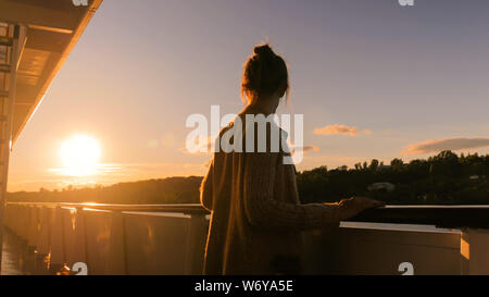 Woman admiring sunset from deck of cruise ship