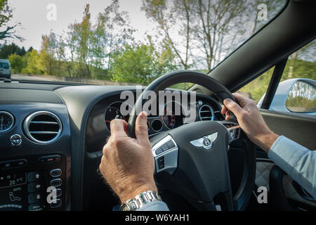 Drivers hands on the steering wheel of a Bentley Continental GTC Supersport Stock Photo