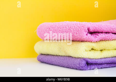 three multi-colored Terry towels have a yellow wall on white background. Copy Space Stock Photo
