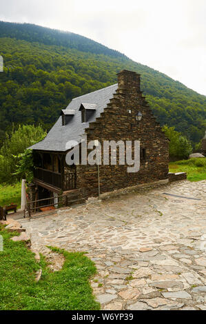 Old stone wall and slate roof renovated house and beech forest in the back (Sant Joan de Toran, Aran valley, Lleida, Pyrenees, Cataluña, Spain) Stock Photo
