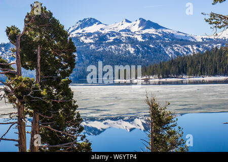 Reflection Of Snow Covered Mountains On Half Frozen Lake Stock Photo