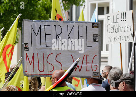 Landau, Germany. 3rd August 2019. A protester holds up a sign that reads 'Merkel has to go'. Around 80 people from right-wing organisations protested in the city of Landau in Palatinate against the German government and migrants. They also adopted the yellow vests from the French yellow vest protest movement. The place of the protest was chosen because of the 2017 stabbing attack in the nearby city of Kandel, in which a 15 year old girl was killed by an asylum seeker. They were confronted by several hundred anti-fascist counter-protesters from different political parties and organisations. Stock Photo