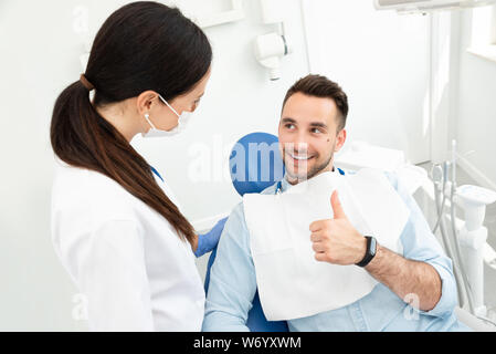 Young doctor dentist and patient showing thumb up. Healthy teeth concept. Stock Photo