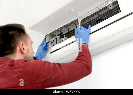 Technician repairing air conditioner appliance. Young man takes care of the cleanliness of the air-conditioning Stock Photo