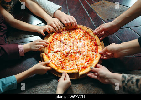 Hands taking pizza slices from wooden table, close up view. Stock Photo