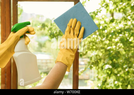 Girl in yellow gloves with a detergent washes plastic windows. Cleaning company for home and window cleaning. Stock Photo