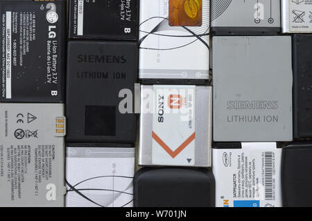 KHARKIV, UKRAINE - JULY 30, 2019: Bunch of old used mobile phone batteries. Recycling electronics was sold in the market cheap. Close up top view Stock Photo